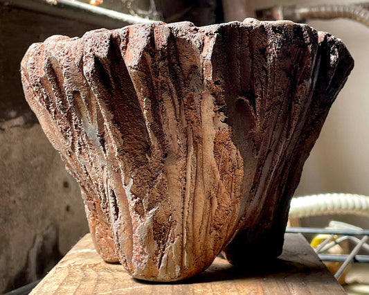 Textured hand-sculpted concrete pot by Mudman on a wood surface